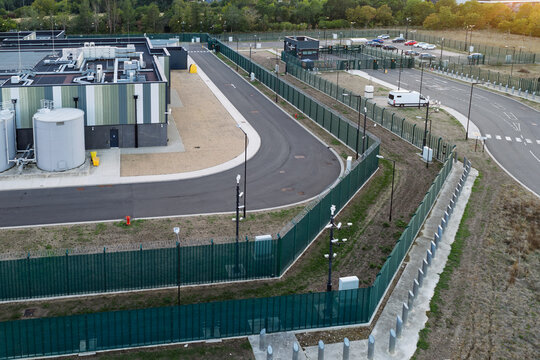 Aerial view of a data center with security fencing, surveillance cameras, and industrial infrastructure in the United Kingdom.