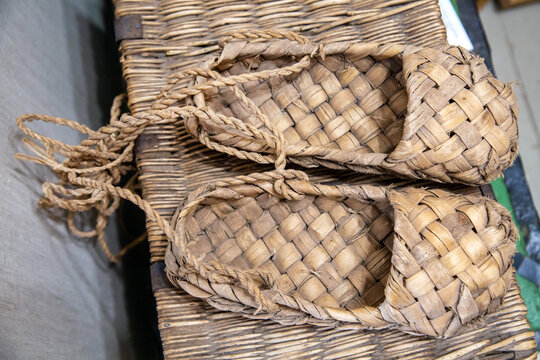 Rustic bast shoes made of bast on a wicker basket. Clothes, shoes, traditions.
