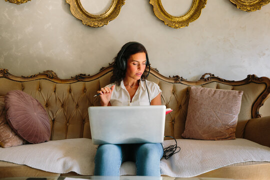 Woman focused on laptop while working from comfortable sofa