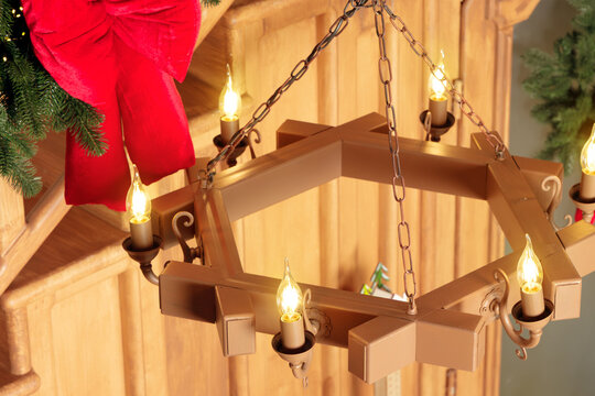 Rustic wooden chandelier with glowing candle bulbs in a festive holiday cottage interior setting