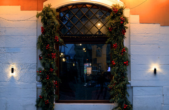 Festive Christmas arch window decorated with evergreen garlands and red ornaments at night