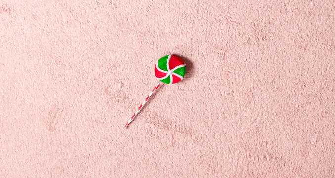 Minimalist art concept single festive lollipop on a soft textured pink background empty copy space