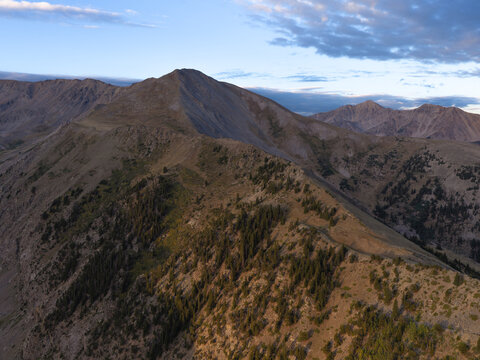 Aerial view of Missouri Mountain and the rugged terrain of the Missouri Gulch Trail with pine forests and rocky slopes under a clear morning sky in Buena Vista, Colorado, United States.