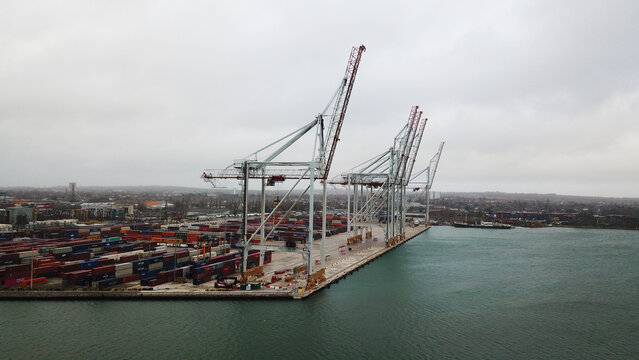 Aerial view of Southampton Port featuring large container cranes and rows of stacked shipping containers along the waterfront under a cloudy sky in Southampton, United Kingdom.
