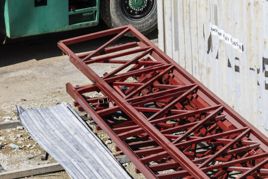 Red metal truss construction site steel structure industrial equipment outdoor sunlight building material ground machinery urban development engineering