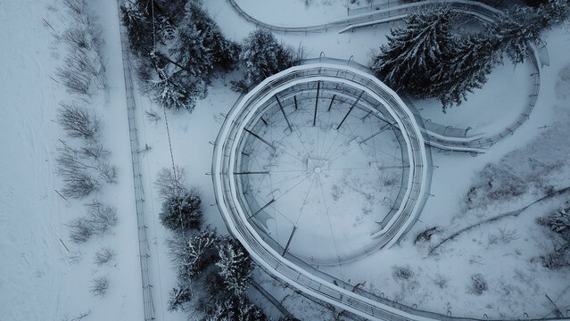 Aerial view of the Col de la Faucille summer sledge track covered in snow, surrounded by snow-covered pine trees in Gex, Auvergne-Rhone-Alpes, France.