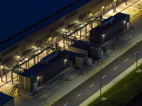 Aerial view of an advanced data center facility with modular units and industrial infrastructure illuminated at night in Warsaw, Masovian Voivodeship, Poland.