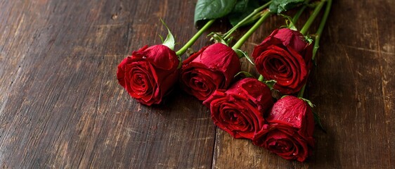Fototapeta premium Five red roses with water droplets arranged on a dark wooden table