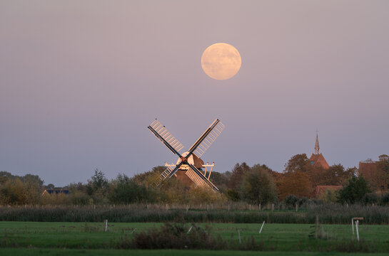 Full moon over a traditional windmill in the Dutch countryside. Groningen, the Netherlands.
