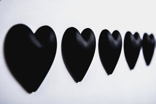 Row of decreasing size black heart shapes on white background