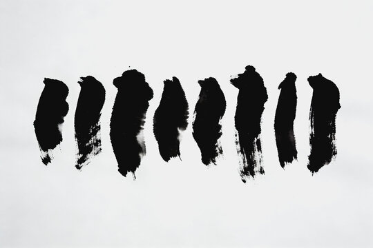 Eight Black Ink Brush Strokes On White Plain Paper Surface
