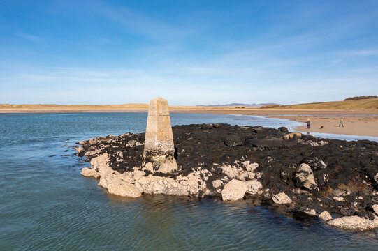 Aerial view of the stone trig point marker on a rocky outcrop covered in seaweed at Ballyness Bay in Ballyness, County Donegal, Ireland.