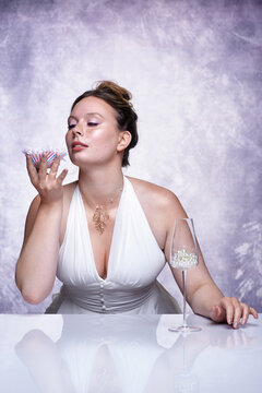Luxury beauty portrait of elegant woman holding chrysanthemum flower near face. Glass filled with pearls.