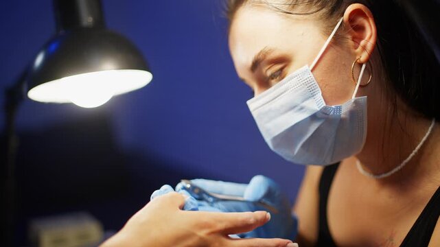 Professional nail technician carefully cuts woman cuticles with manicure nippers during salon manicure procedure focused on nail care healthy hands and elegant appearance. High quality 4k footage