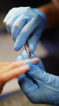 Female client receives professional manicure as nail technician trims cuticles with nippers in beauty salon during detailed nail care and feminine beauty procedure. High quality 4k footage