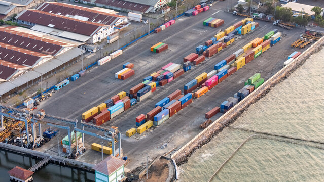 Semarang, Central Java, Indonesia - 27 September 2026: Aerial view of a busy container terminal with colorful shipping containers, industrial cranes, and warehouses along the coast.