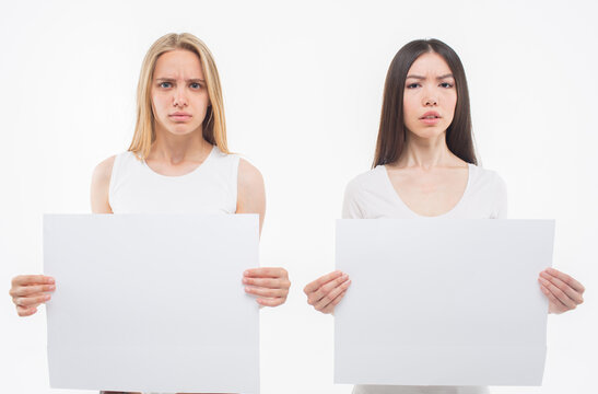 Emotional and disturbed young women look on camera. Ech hold square pieces of paper. Isolated on white back background.