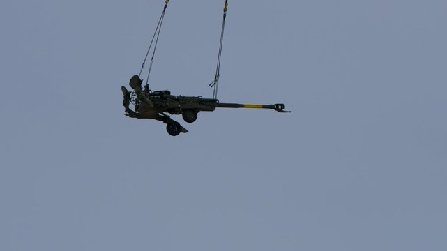 Large canon being flown in with a helicopter