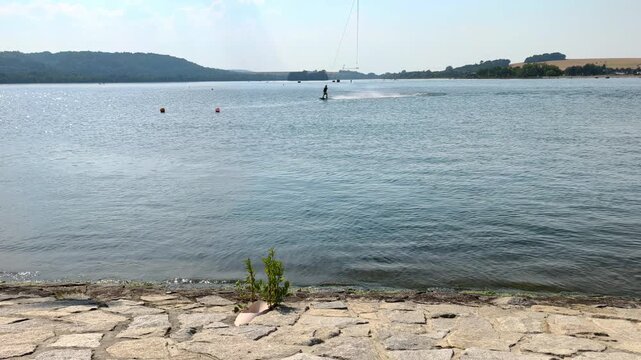 Slow motion shot of a water skier gliding across the surface and creating a trail of water spray.