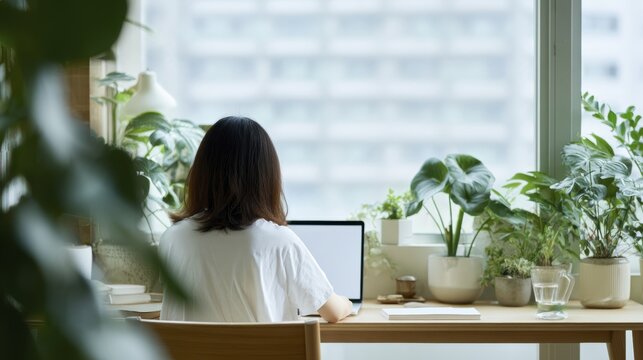 Remote work inspiration: woman at desk with green plants and bright urban background
