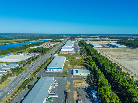 Wilmington, North Carolina, United States - 27 September 2026: Aerial view of industrial warehouses and distribution centers located along a highway surrounded by forest and wetlands.