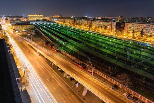 View of the Gara de Nord railway station at night with long exposure light trails from traffic on the adjacent road and illuminated train tracks in Bucharest, Bucharest, Romania.