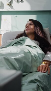 Positive woman patient talks to doctor as lies calmly in bed