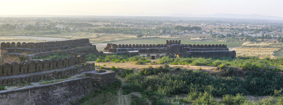 View of Rohtas Fort with its historic stone battlements and defensive walls overlooking the surrounding landscape and distant town in Dina, Punjab, Pakistan.