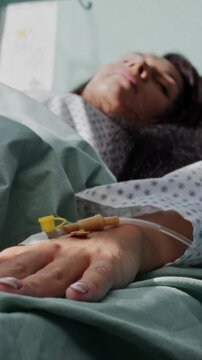 Woman patient with hand IV sleeps unquietly in comfortable bed