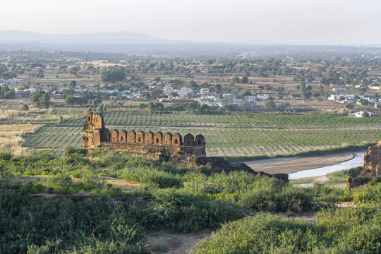 View of the historic stone walls of Rohtas Fort overlooking the rural landscape, agricultural fields, and a winding stream in Dina, Punjab, Pakistan.
