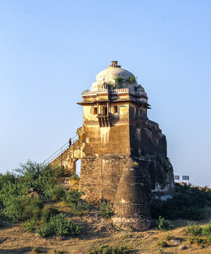 View of the historic Rohtas Fort tower with stone walls and a dome, featuring a person walking up the stairs on a sunny day in Dina, Punjab, Pakistan.