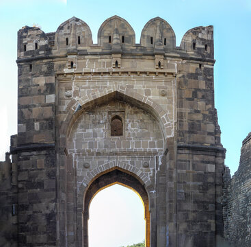 View of the historic stone gateway of Rohtas Fort with intricate architectural details and battlements against a clear blue sky in Dina, Punjab, Pakistan.