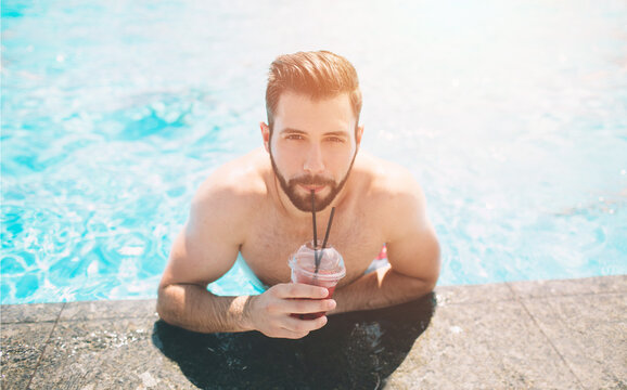 Summer photo of muscular smiling man in swimming pool. Happy male model in water on summer vacations.