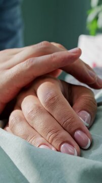 Man takes hand of beloved wife severe patient lying in bed