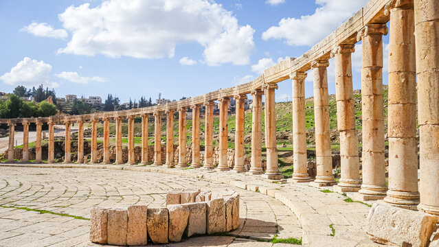 View of the ancient Roman Oval Plaza with its iconic colonnade and stone paved ground in Jerash, Jerash Governorate, Jordan.