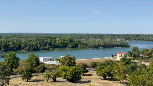 A beautiful view on Danube river, Belgrade, Serbia. Aerial panoramic view of broad river, wooded shoreline, parkland, waterfront buildings, and distant city skyline under clear blue sky