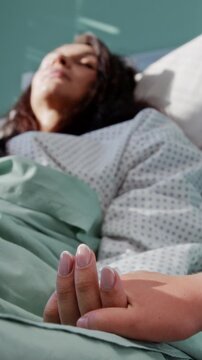 Girl comforts mother through gentle hand touch in hospital ward