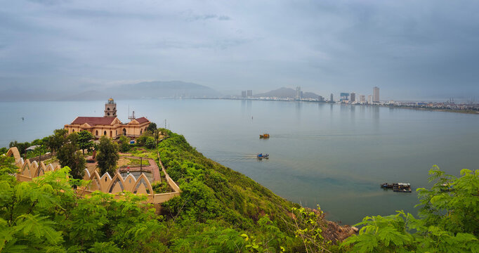 View from Phuoc Mai Lighthouse to Quy Nhon city with fishing boats in foreground, Vietnam. Scenic coastal view from Hai Minh peninsula with lighthouse, sea, mountains, and cityscape.