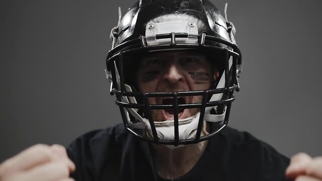 Dynamic video footage of an American football player expressing raw emotion, shouting, and celebrating a winning moment after an intense game. Features dramatic energy with sweat and water droplets fl