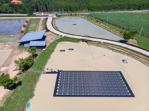 Top down aerial view of a floating solar cell farm on a pond in a rural agricultural landscape. Sustainable green energy and eco-friendly technology concept. Human-created, not AI.