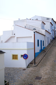 Steep Cobblestone Street with Traditional White and Blue Houses in Portugal