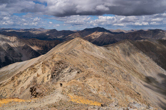 View of the rocky ridge of Mount Missouri in the Collegiate Peaks Wilderness with a hiking trail and dramatic clouds under morning light in Buena Vista, Colorado, United States.
