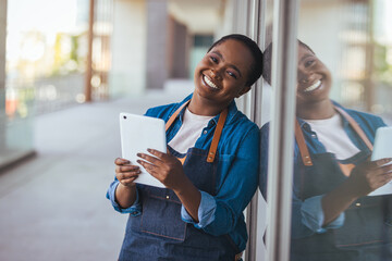 Smiling Female Shop Owner Using Tablet Outside Small Business Storefront Leaning on Glass © Dragana Gordic