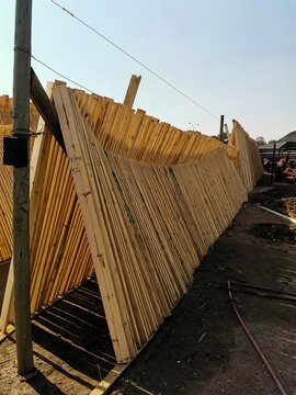 View of neatly stacked wooden planks and poles in a timber yard, showcasing natural textures and organized lumber preparation in Pretoria, Gauteng, South Africa.
