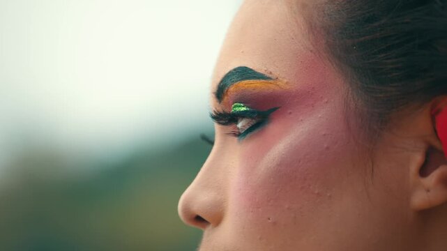 A detailed side profile macro shot of a woman's eye area, showcasing the heavy and colorful stage makeup typical of Indonesian traditional dance.
