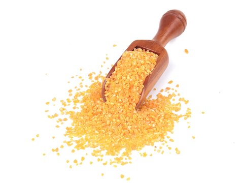 Cracked corn or yellow corn grits served in a wooden scoop with a scattered pile, isolated on a white background. Perfect for animal feed, agriculture, bird food, and traditional ingredients