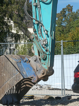 View of a heavy excavator bucket and hydraulic arm at a demolition and road construction site in Garching, Bavaria, Germany.