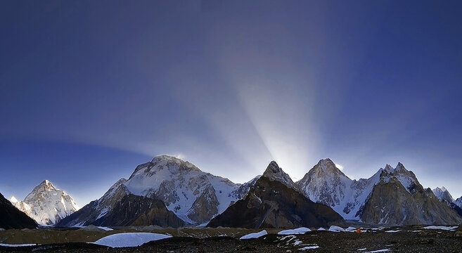View of Karakoram peaks including K2, Broad Peak, Gasherbrum IV, and Gasherbrum I from the Concordia Campsite with snow-capped summits and sun rays in Skardu, Gilgit-Baltistan, Pakistan.