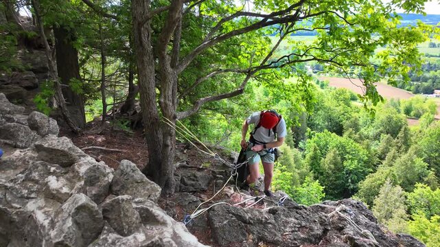 Rock climber preparing equipment for rappelling down a cliff at Rattlesnake Point