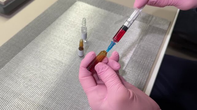 Woman in medical protective gloves drawing medication into syringe from ampule top view